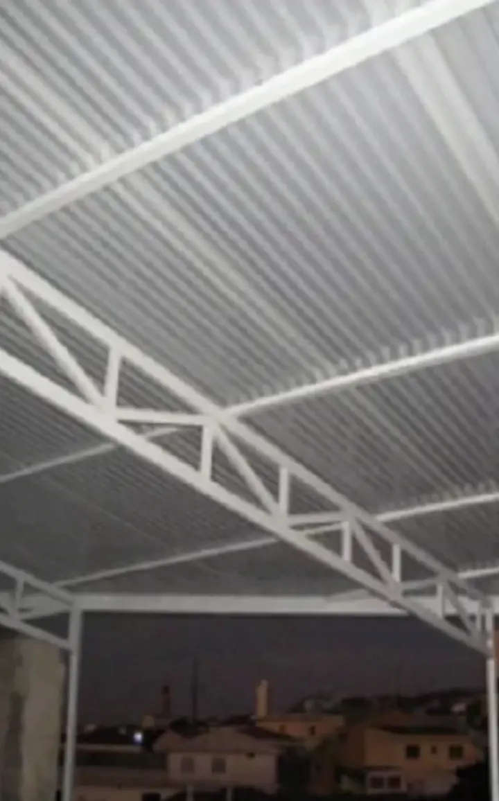 Estrutura metálica com treliças e telhas iluminada à noite