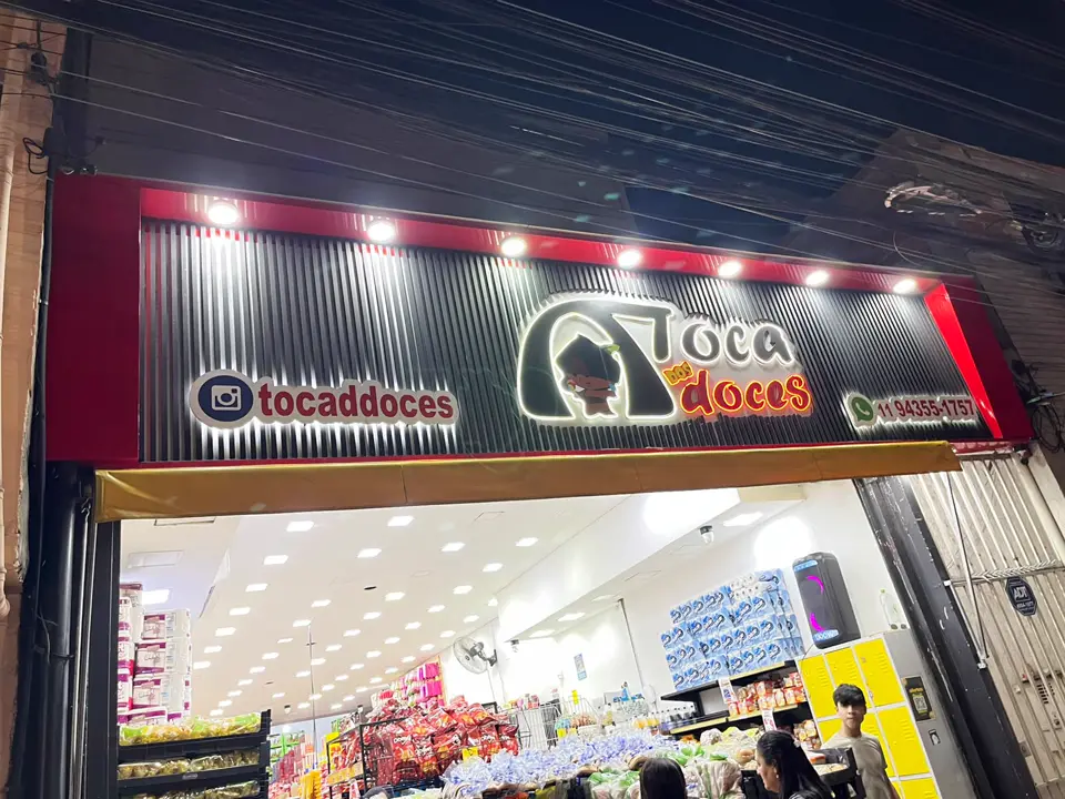 Fachada da Toca dos Doces à noite com letras caixa iluminadas e spots de LED